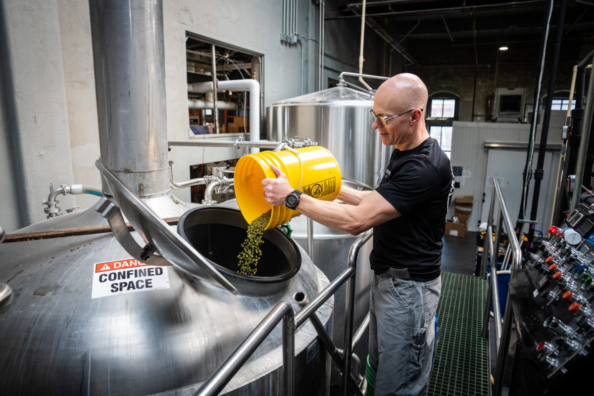 Brewer pouring hops into brew kettle at Rhinegeist