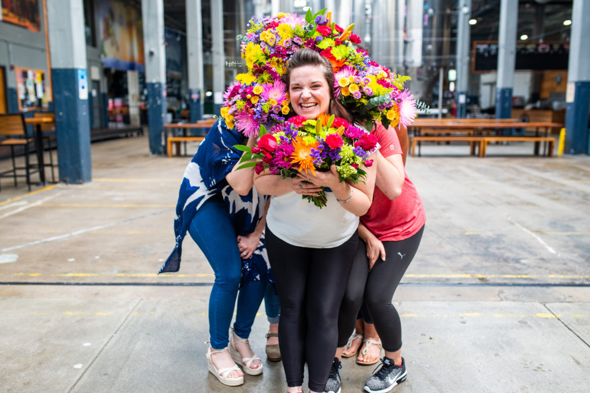 Group of women peaking through flower wreath in Rhinegeist taproom