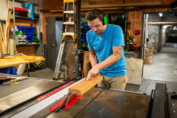 man in woodshop cutting plywood with buzzsaw