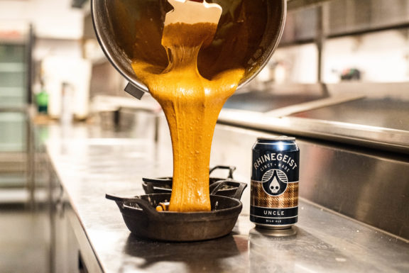 Cake batter being poured next to can of rhinegeist uncle