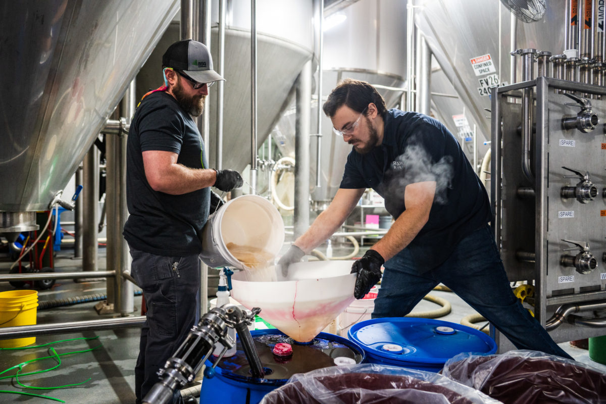 two brewers pouring liquid