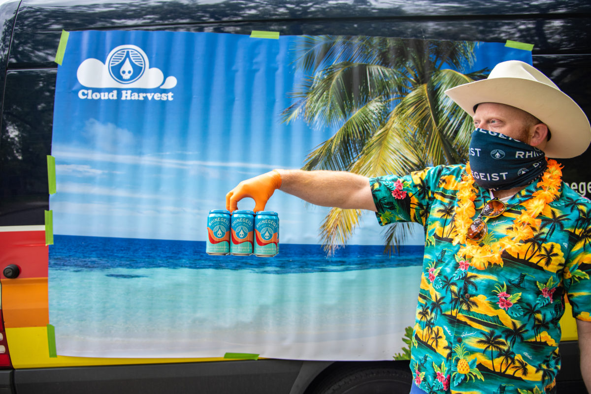 man holding six pack in front of beach backdrop